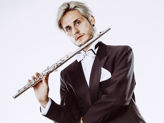 Male flutist wearing tailcoat holds flute
