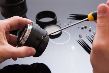 Photo camera lens repair set. Technician engineer check optics alignment and maintenance support of broken photographic 50 1.4 photo camera lens part. Pov to workplace and engineer's hands.