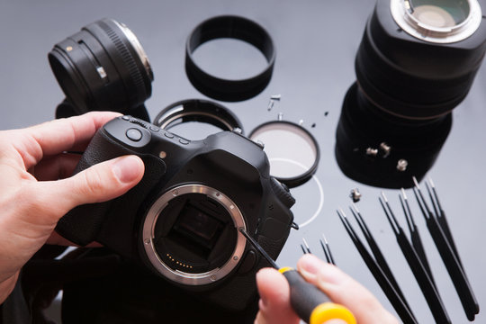 Photo camera repair set in laboratory. Maintenance support of professional photo camera and lenses by engineer. Optical dslr lens and video equipment service