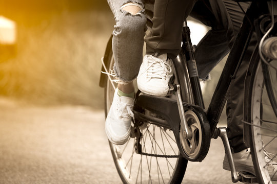 Leg and feet of young couple riding a bicycle together in vintage color tone