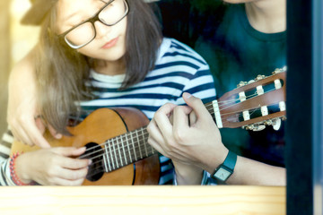 Fototapeta premium Young love couple playing guitar together in the cafe in vintage color tone