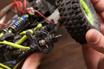 Rc radio control car crawler model whell repair on wooden background. Green toy suv in repairshop workplace, free space