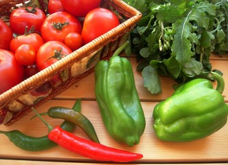 Paprika, tomatoes, hot chili pepper and arugula on a rustic table........