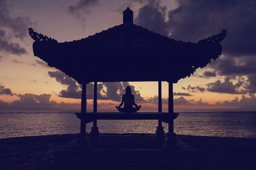 Woman practicing yoga on the beach.