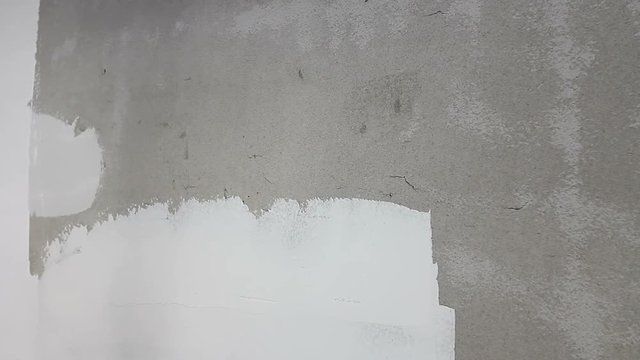 Painter is smoothing wall before painting with trowel, skim coating
Worker is applying skim coating material to the ceiling, wall before painting.
