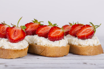 Sandwich of strawberry and cottage cheese on the wooden table, close up