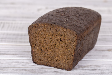 A loaf of rye bread on white wooden background