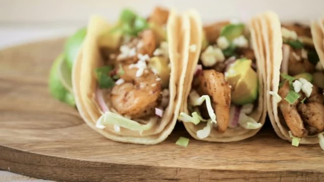 Close up of fresh chipotle shrimp tacos with cotija cheese on a white corn tortillas