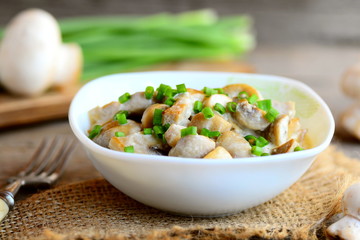 Mushrooms in a sour cream sauce. Mushrooms stew with sour cream and fresh green onions in a bowl. Healthy vegan recipe. Fresh mushrooms, green onions, burlap textile on vintage wooden table