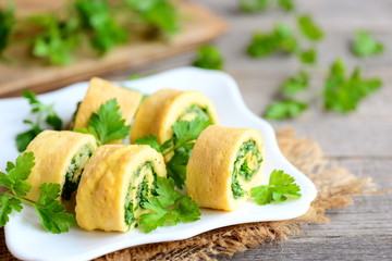 Cheese and parsley omelette rolls on a white plate. Home fried omelette rolls with grated cheese and finely chopped parsley. Tasty low carb egg omelette recipe. Rustic style
