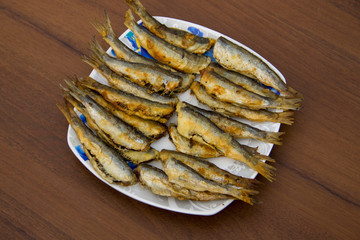 Fried baltic herring on a plate on wooden background