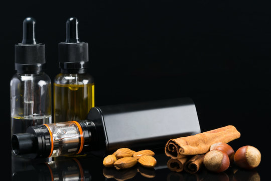 Black powerful electronic cigarette next to liquids, with the taste of nuts and carica