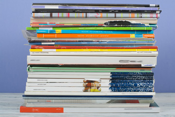 Open stacking book, hardback colorful books, magazine on wooden table and purple background. Back to school. Copy space for text. Education business concept.