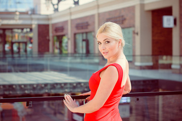 A beautiful blonde woman in a dress in the city on a walk, waiting for a date