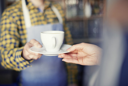 Waiter giving cup of coffee to customer