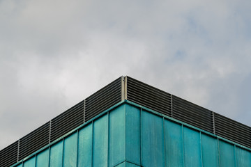 Fototapeta na wymiar Green metal facade over cloudy sky