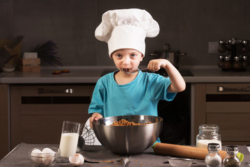 Boy in chef hat cooking in the kitchen.