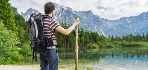 Hiking tourist from behind and lake near Alps in Almsee in Austria. Panoramic photo.