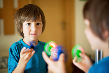 Little child, boy, playing with green and blue luminous fidget spinner toy to relieve stress - obrazy, fototapety, plakaty