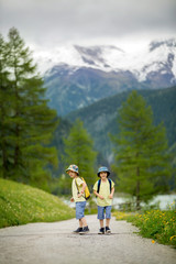 Fototapeta na wymiar Two children, boy brothers, walking on a little path in Swiss Alps