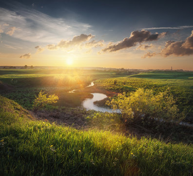 there is a small stream among spring fields