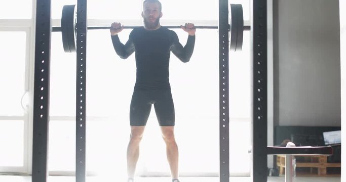 Young Man Exercising Doing Weighted Squats On Smith Machine During Workout Training At Gym Male Athlete Fitness