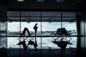 silhouette of a girl in an empty airport terminal with view of the runway