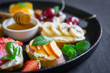 Dish with summer fruit berries nuts honey sandwiches. Selective focus