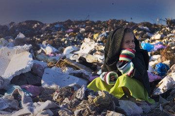 A sad child in a garbage dump after a hard day's work