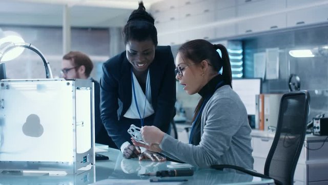Black and Caucasian Female Scientists Working on a Computer, Correlating Their Notes and Experience. They Work in a Modern Laboratory/ Research Center.Shot on RED EPIC-W 8K Helium Cinema Camera.