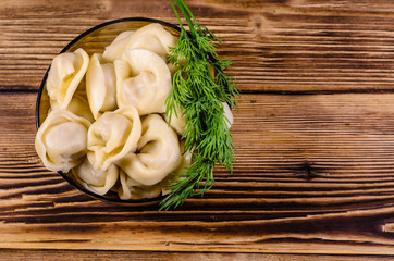 Fresh dumplings in glass bowl on wooden table. Top view