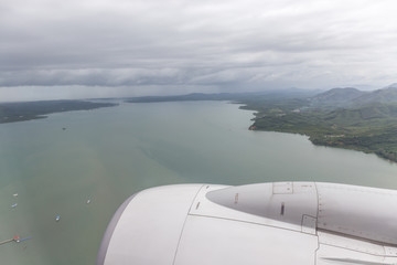 Fototapeta na wymiar Panoramic natural view from airplane window, white fluffy clouds over the Rock Mountain and ocean in southern of Thailand.
