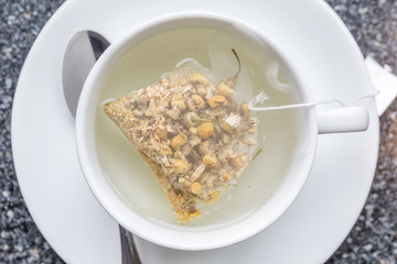 The aroma chamomile tea bag floating on white teacup, ready to served in afternoon tea.