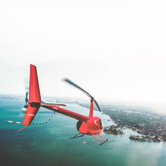 Roter Helikopter fliegt über Wasser auf Inseln zu © nik0.0kin