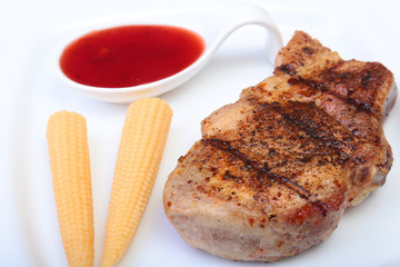 grilled pork chop with Cranberry sauce and Mini Corn cob preserved on plate on wooden board
