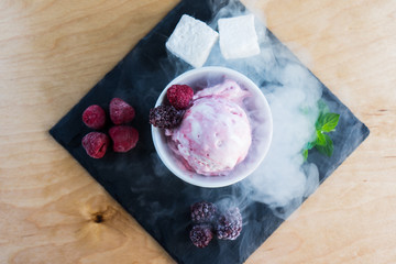 The white-pink ice cream top with berries and steam on the slate