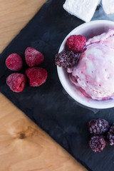 The white-pink ice cream top with berries and steam on the slate