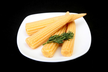 Mini Corn cob preserved on plate on wooden board.