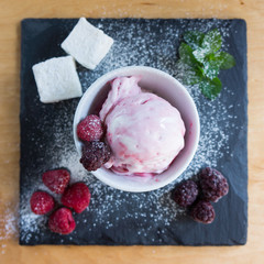 The white-pink ice cream with sugar powder berries on the slate