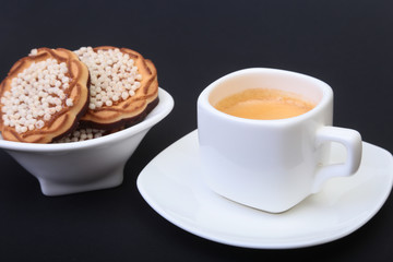 Classic espresso in white cup with homemade cake on black background. Selective focus.
