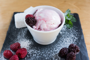 The white-pink ice cream with sugar powder berries on the slate