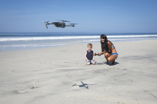 Young woman and boy on the beach flying drone