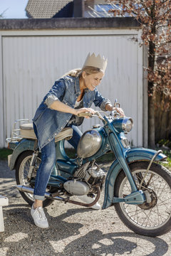 Happy woman on vintage motorcycle wearing a crown