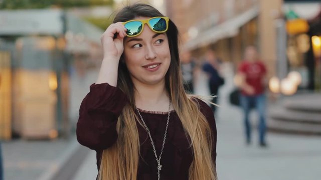 Pretty woman posing with sunglasses in city