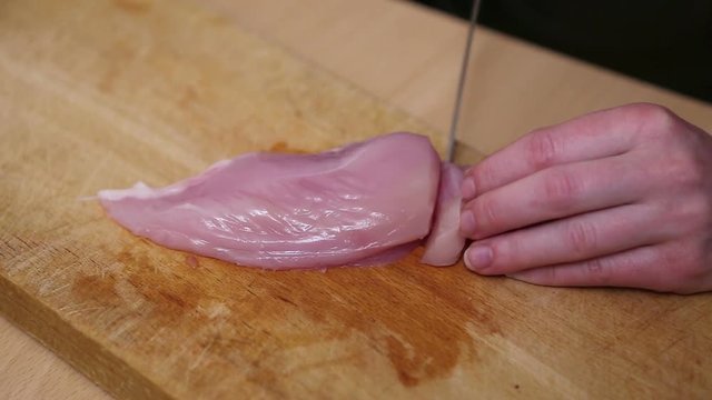 Sliced raw chicken on wooden cutting board 
