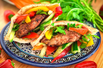 Pita bread with fried pork chop and vegetable, olive, spring picnic. Wooden background. Close-up. Top view