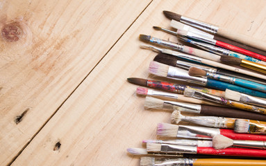 Fototapeta premium Paints, brushes and palette on the white wood background. The workplace of the artist. Banner for school