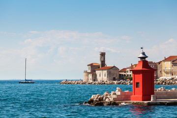 Cityscape of the old city Piran with historical medieval and new red lighthouses in summer.