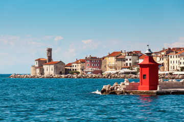 Cityscape of the old city Piran with historical medieval and new red lighthouses in summer.
