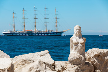 View with stone sculpture of a mermaid in city of Piran and large sailing ship on background, Slovenia